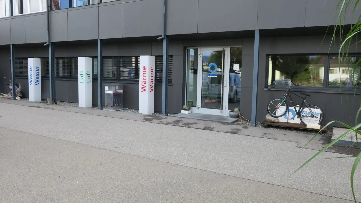 Eingang des Betriebsgebäudes in Altach mit den Säulen Wasser, Luft und Wärme