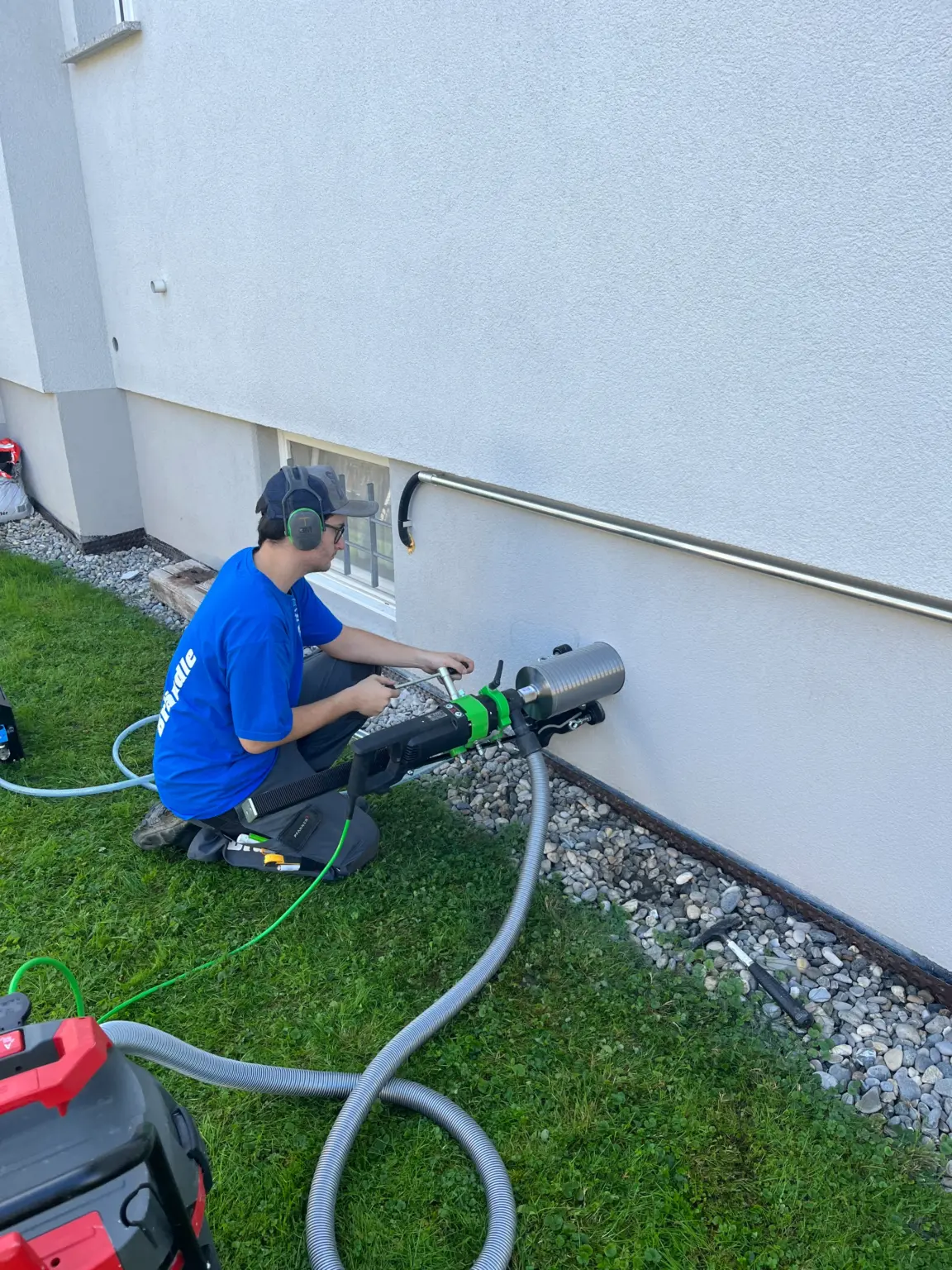 Lehrling bei der Kernbohrung an einer Hauswand