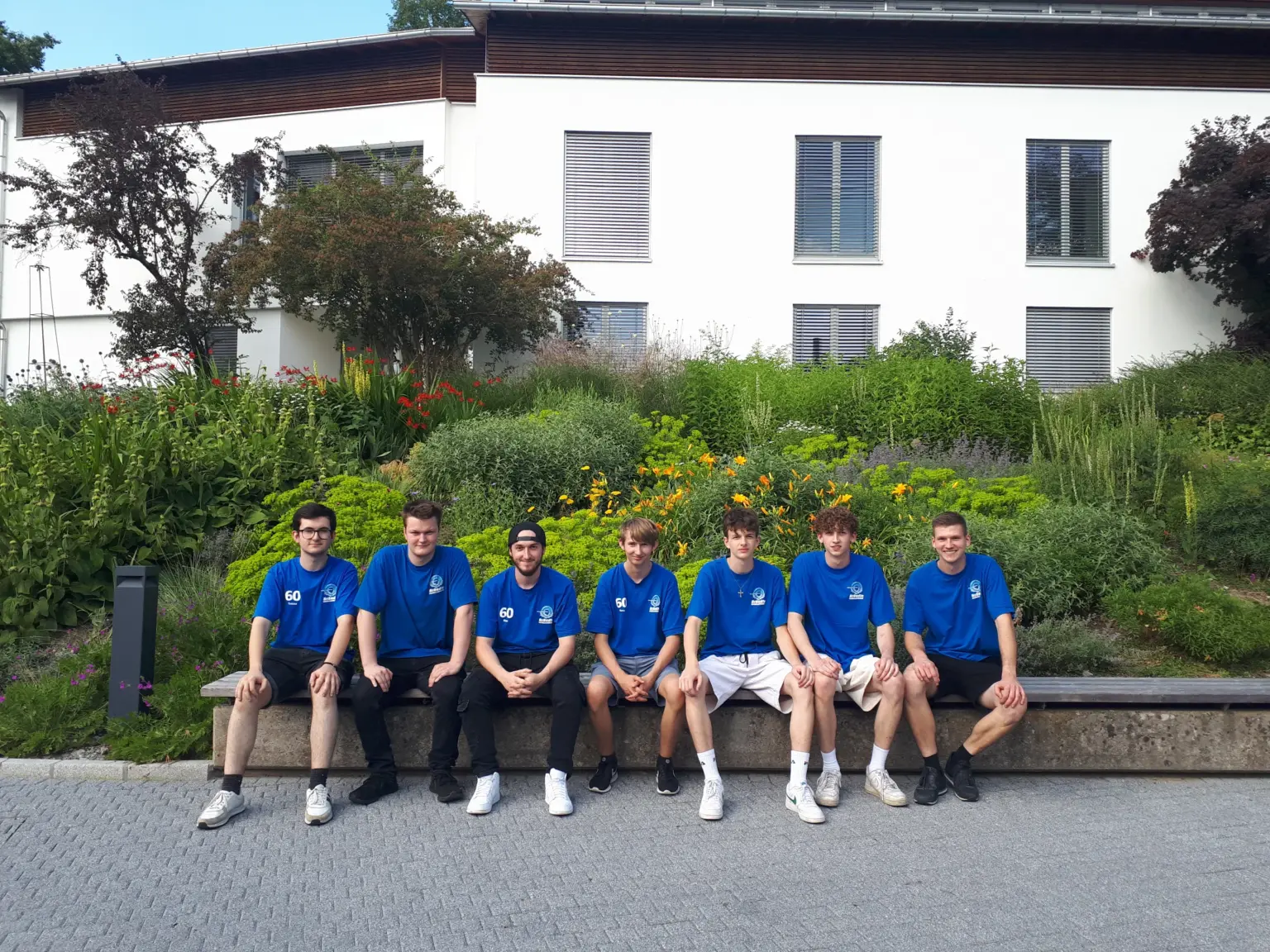 Lehrlinge in blauen Brändle-Shirts sitzen beim Lehrlingstag gemeinsam auf einer Mauer